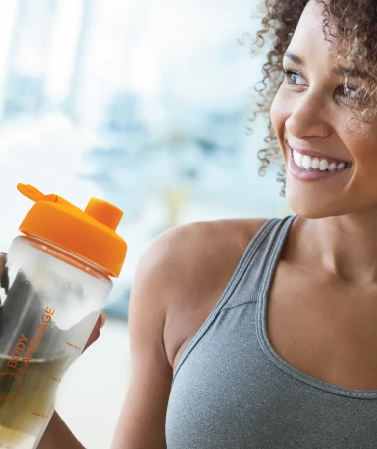 Une femme souriante buvant un verre d'aloe vera à boire, illustrant les bienfaits de la cure ALOEL